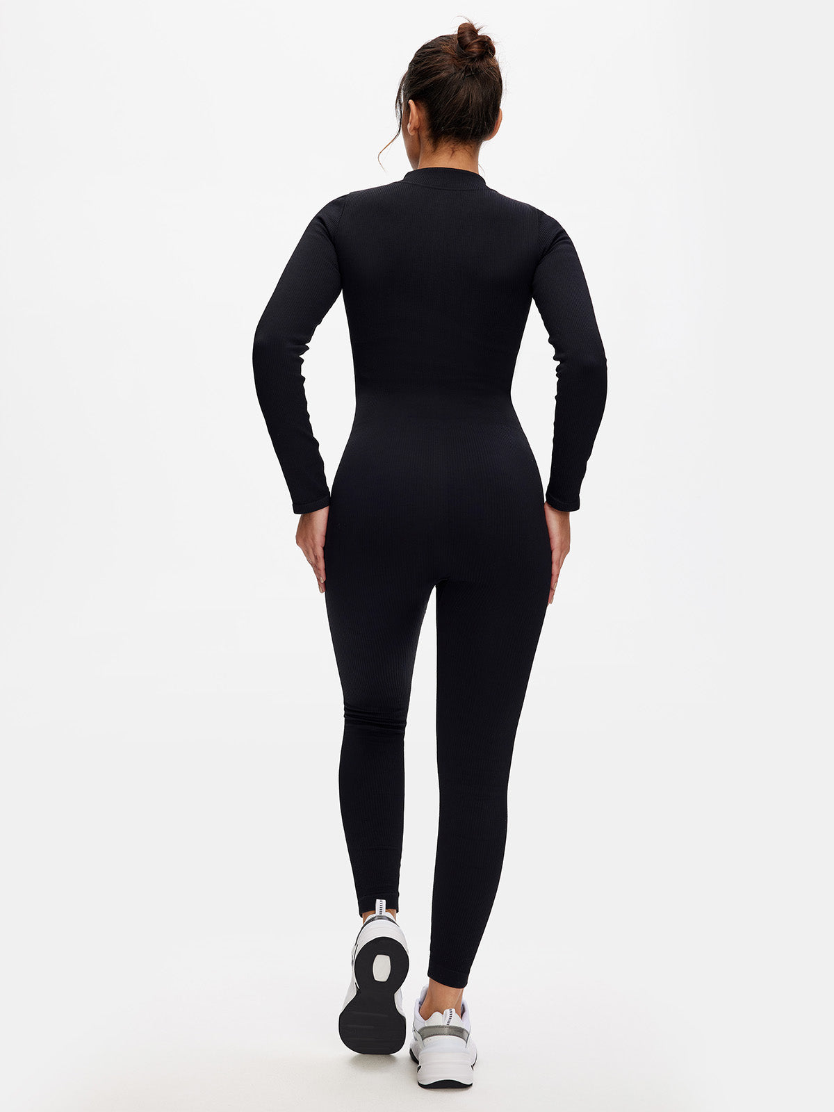Rear view of black long sleeve jumpsuit showing seamless ribbed fabric and contour-hugging design.