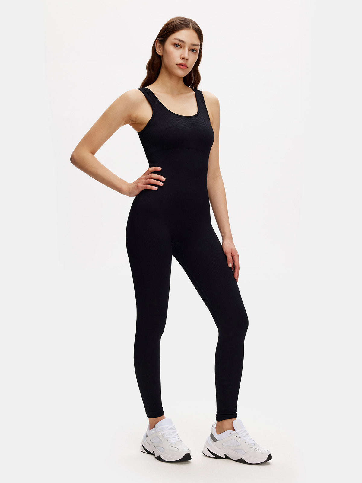 Woman wearing black ribbed bodycon jumpsuit with scoop neck and sleeveless design, perfect for workouts or casual wear.