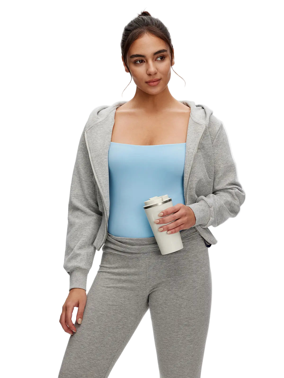 Woman wearing a gray hoodie and pants, holding a coffee cup on a white background