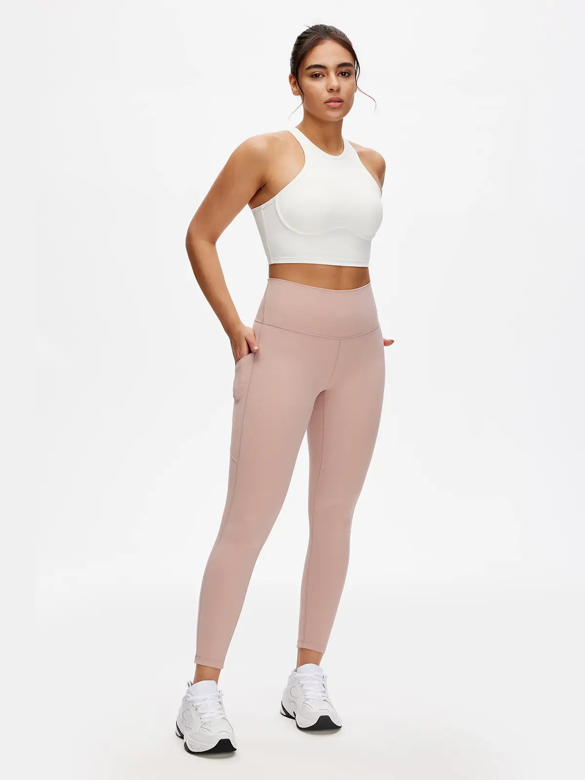 Woman wearing a white crop top and pink leggings on a white background