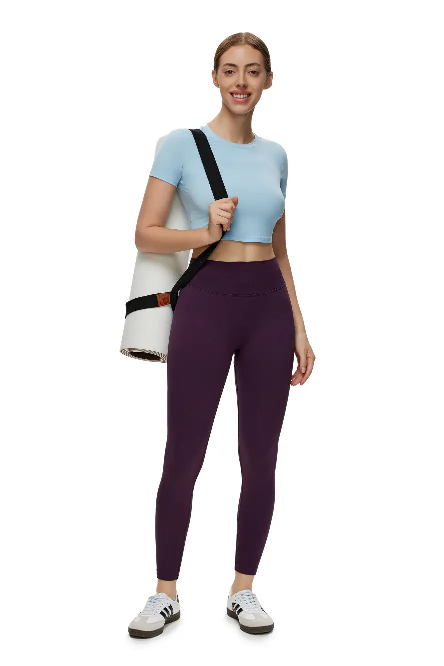 Woman in athletic wear holding a yoga mat bag on a white background
