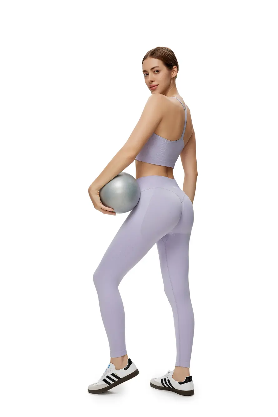 Woman in lavender athletic wear holding a silver ball on a white background