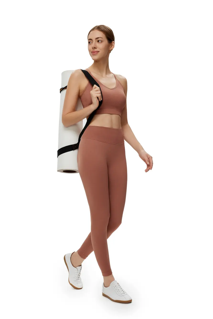 Woman in brown athletic outfit holding a white and black bag on a white background