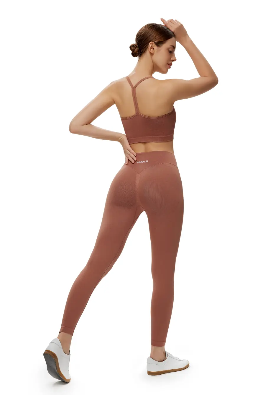 Woman wearing a brown sports bra and leggings set on a white background